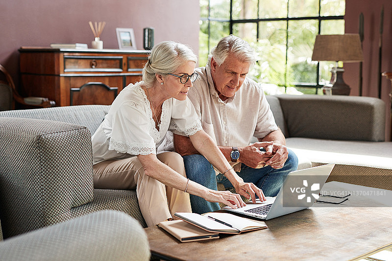 一对成熟的夫妇在家里用笔记本电脑计算他们的财务图片素材