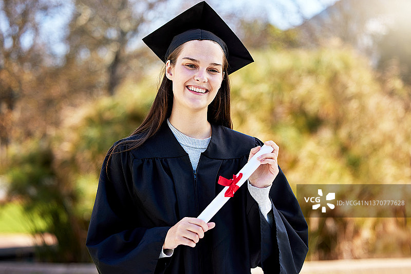 一名年轻女子在毕业典礼上手持毕业证的肖像图片素材