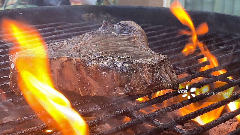 多汁的肋眼牛排在烤架上被老式木炭烧烤的火亲吻。图片素材