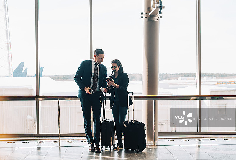 在机场候机楼使用手机携带行李的全程商务夫妇图片素材