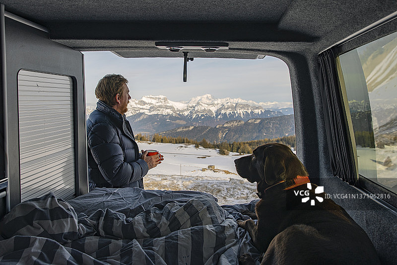 一名男子在他的露营车后面喝着茶，眺望着法国的阿尔卑斯山图片素材