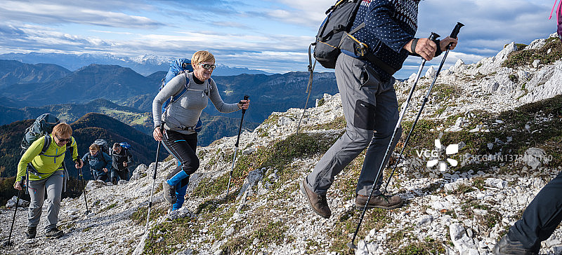 一群快乐的徒步旅行者在岩石上一排走到山顶图片素材