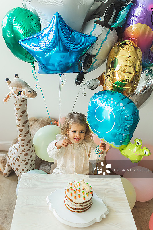 小女孩吹蜡烛庆祝她的2岁生日。图片素材