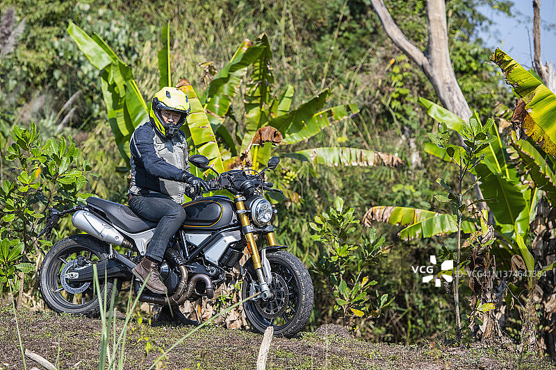 一名男子骑着他的扰频器式摩托车在泰国崎岖的地形上行驶图片素材