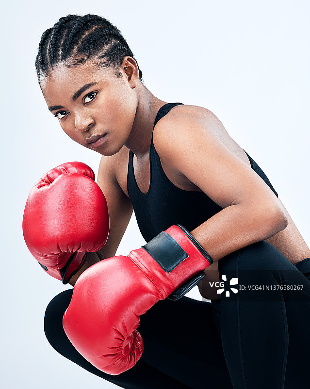 摄影棚拍摄的一个运动的年轻女子戴着拳击手套，在摄影棚的背景下摆姿势图片素材