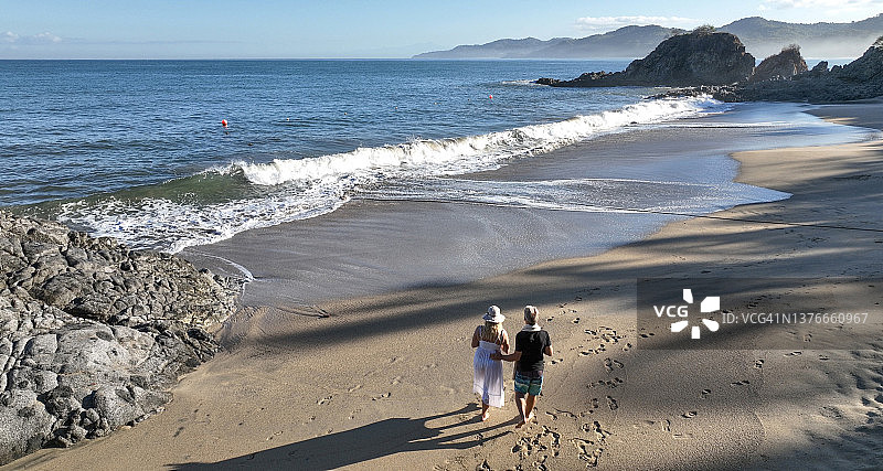 一对夫妇在沙滩上散步的鸟瞰图图片素材