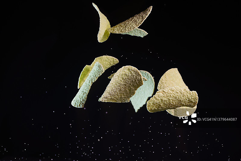 黑色背景的鳄梨薯片在半空中飞舞图片素材