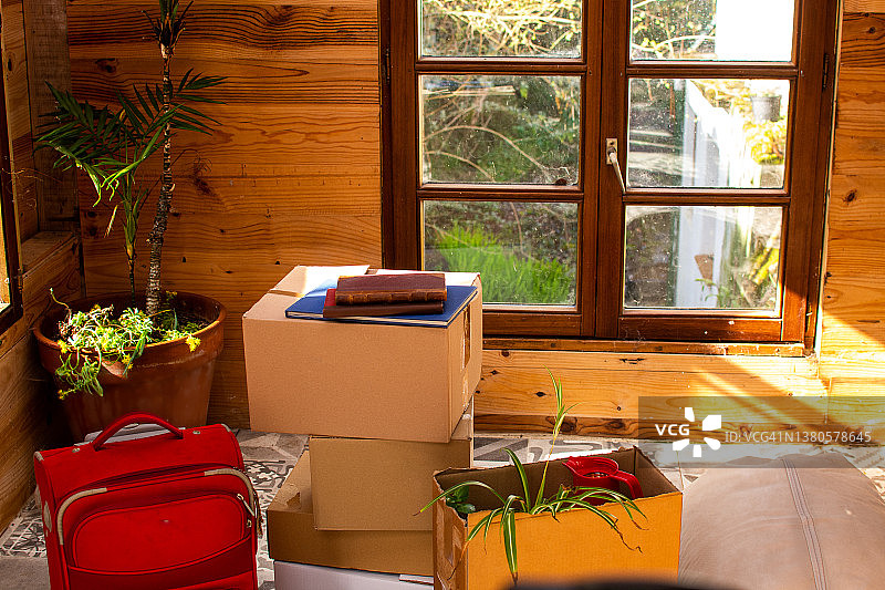 在一所乡村房子的内部，移动着纸板箱和一个红色手提箱图片素材