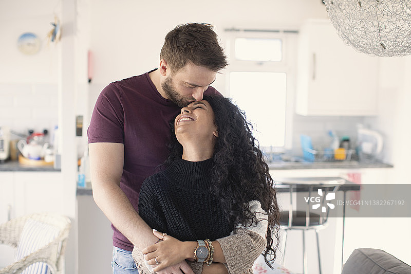 幸福的情侣在厨房里拥抱亲吻图片素材