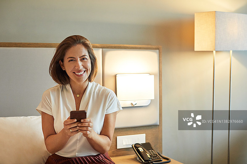 微笑的企业家在酒店使用智能手机图片素材