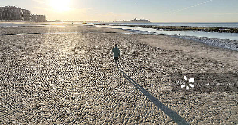 鸟瞰图，男子奔跑在空旷的海滩上图片素材