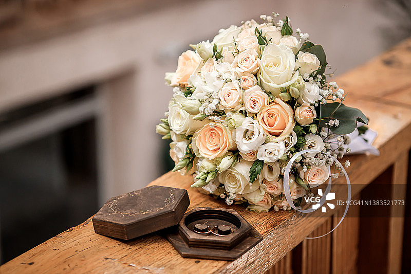 结婚戒指放在一个漂亮的盒子里，旁边是新娘的花束图片素材