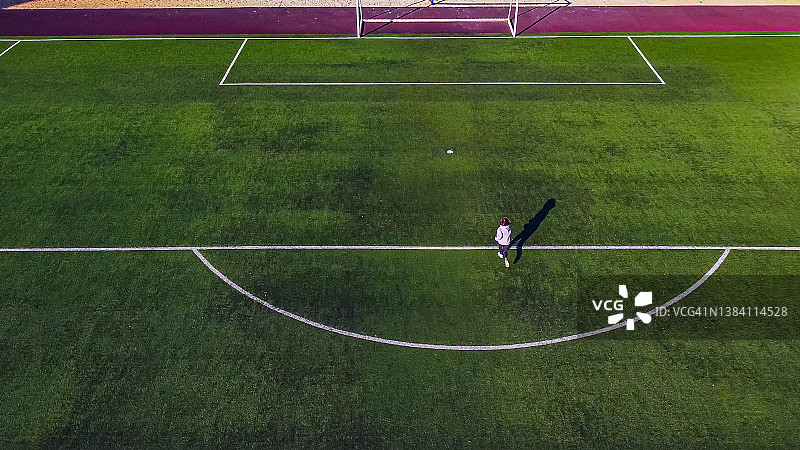 航拍:一个十几岁的小女孩快速跑过足球场，渴望胜利图片素材