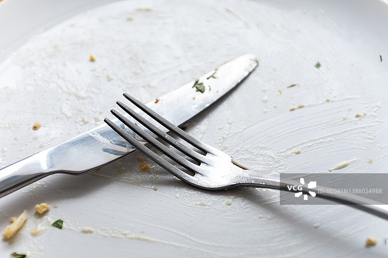 木桌上有一个又脏又空的盘子和刀叉。象征午餐或晚餐结束的餐具。图片素材