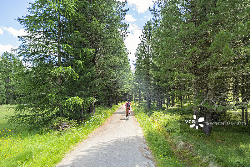 夏天，瑞士恩加丁，一名女子骑着自行车。图片素材
