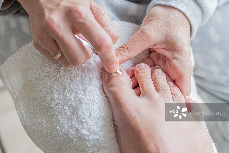 美容师的手在给客户的脚做足疗，把指甲上的角质层去掉。美容美体护理理念图片素材