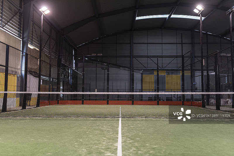 室内的桨球场有它的网，球拍，球。那里没有人，用人造光照明图片素材