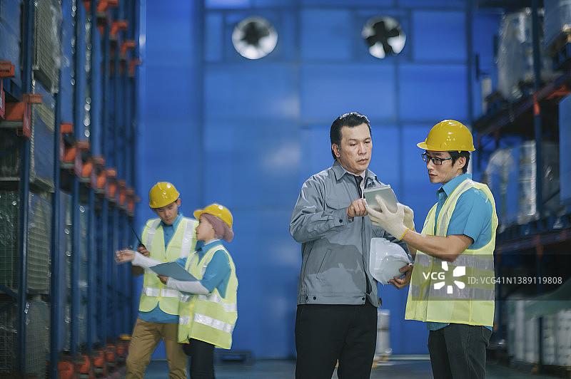 亚洲工厂经理与仓库领班讨论使用平板电脑进行仓库交货计划图片素材
