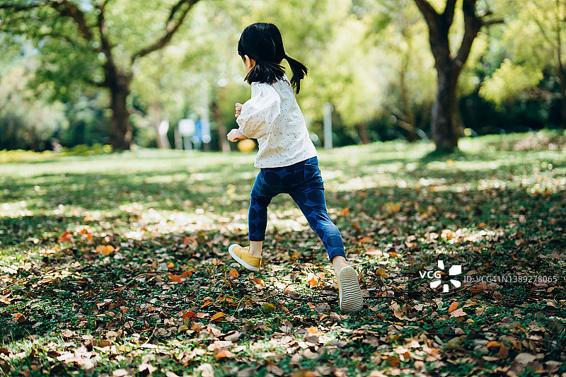 快乐的小亚洲女孩在户外玩得开心，在公园的草坪上奔跑，享受大自然。畅快自由的理念图片素材