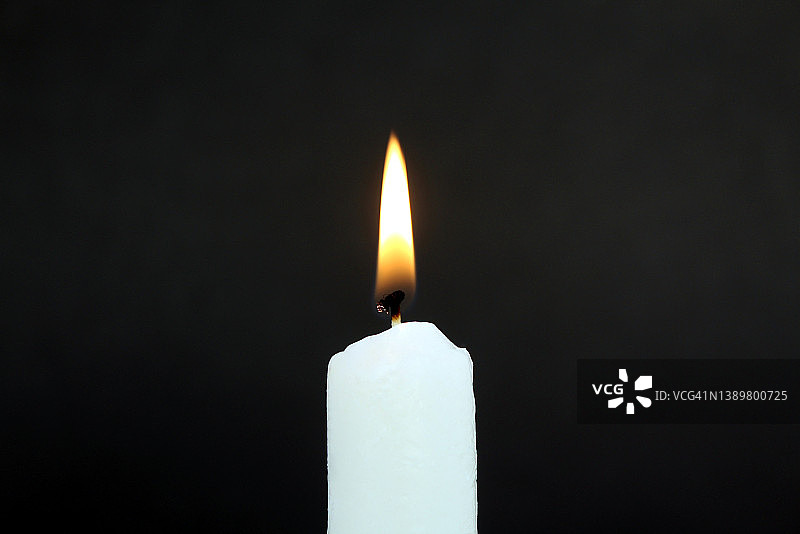 蜡烛在黑色的背景上燃烧。图片素材