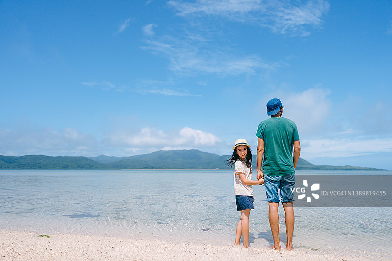 父亲和小女儿站在热带海滩上图片素材