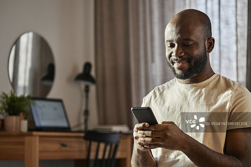 微笑的男人在家里用智能手机图片素材