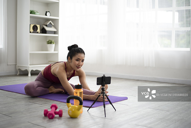 亚洲女性根据在线瑜伽视频在家锻炼。图片素材