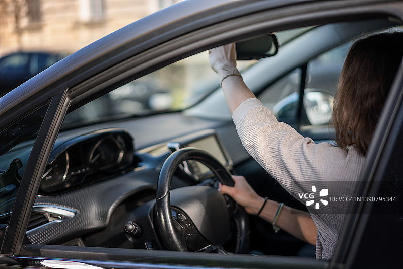 一名女子坐在车里调整后视镜时，在驾驶座上撕扯方向盘图片素材