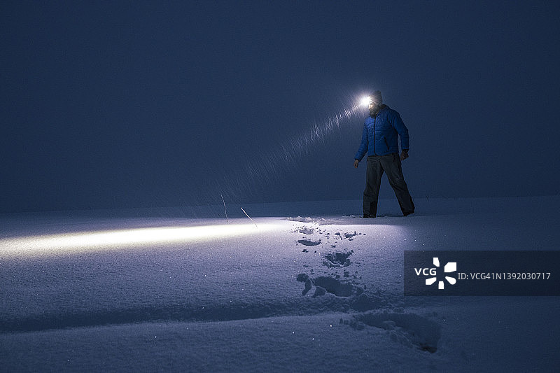男人在深夜深雪中寻找道路。图片素材