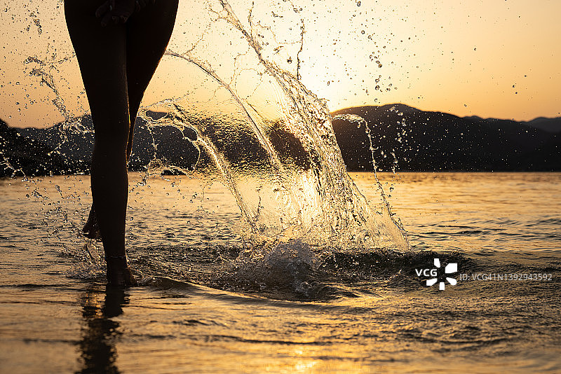 在日落时，一个陌生的女人从海里溅起水图片素材