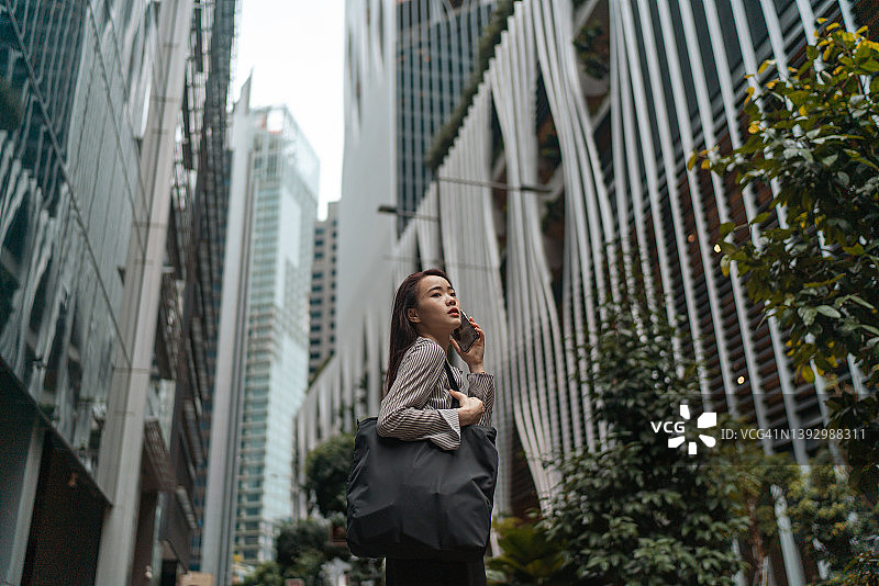 美丽的亚洲女性使用手机对城市背景图片素材