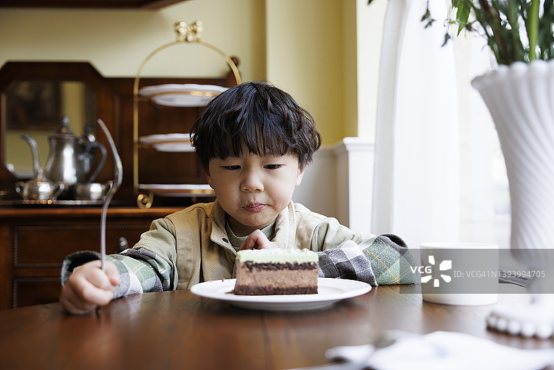 一个小男孩在厨房里吃蛋糕图片素材