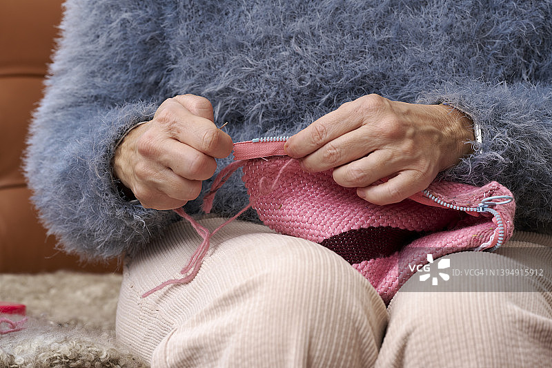 一位女士在织羊毛，她在缝拉链，她在网上学习，她在家用织布机织布图片素材