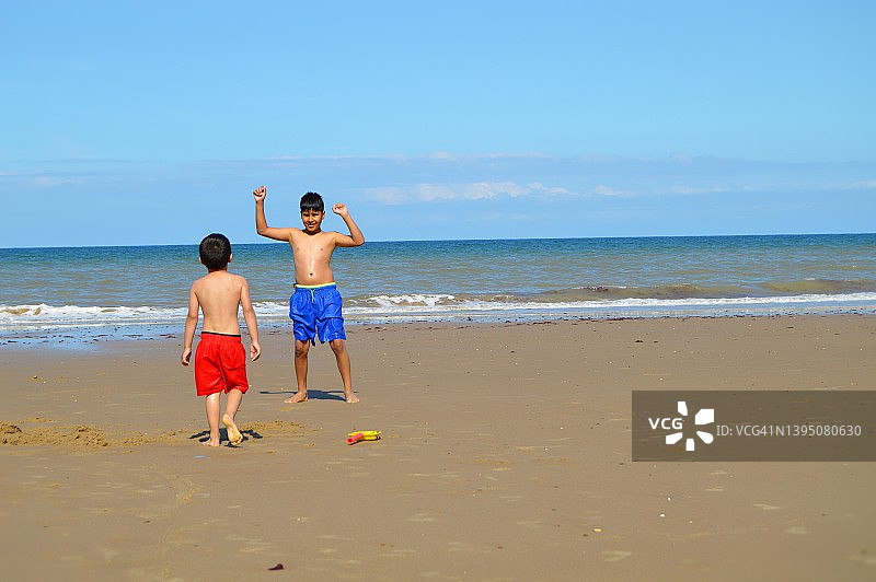 两个快乐的男孩的偷拍，兄弟姐妹的孩子在沙滩上玩，附近的海浪在夏天的一天，在海边，天空和太阳图片素材