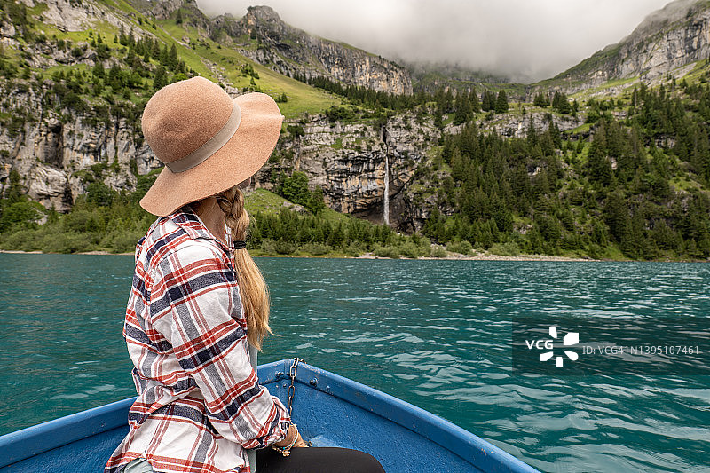快乐的年轻女子放松在划船而巡航在高山湖泊在夏天图片素材
