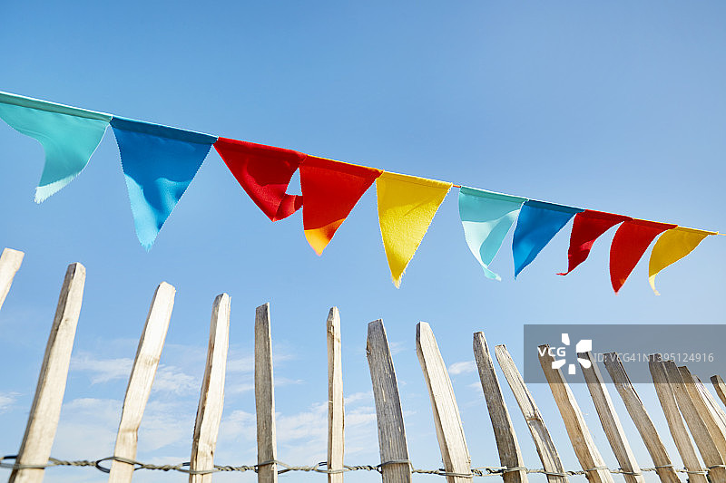 低角度视角的彩色三角旗链派对装饰在栅栏对蓝天图片素材