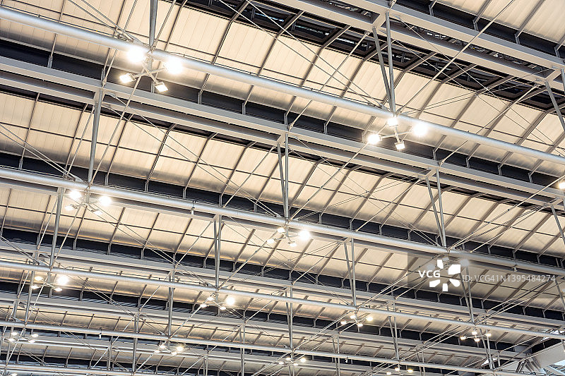 现代仓库、购物中心、写字楼或其他商业地产的天花板上有明亮的灯光。天花板下导轨上的定向LED灯图片素材