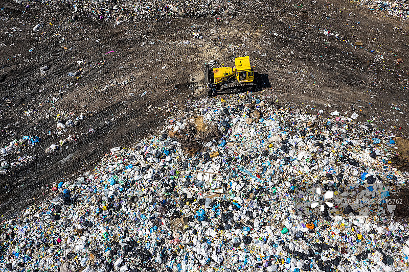 城市垃圾场推土机的鸟瞰图。污染和过度消费的概念图片素材