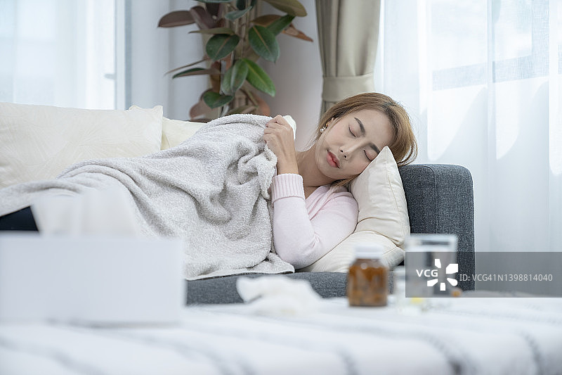 一个发高烧的女人躺在家里的沙发上图片素材