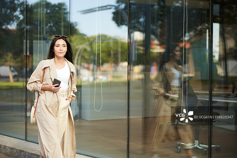 一位女商人走在一座办公楼前。图片素材