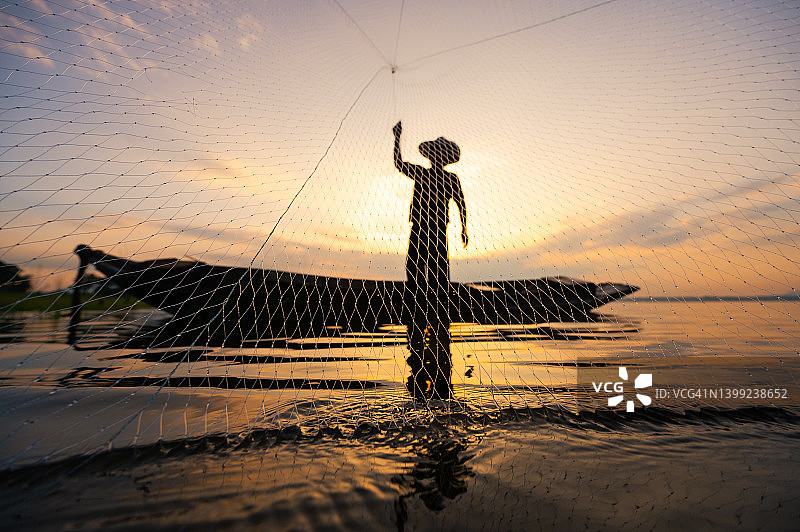 剪影渔夫站在船上扔渔网图片素材