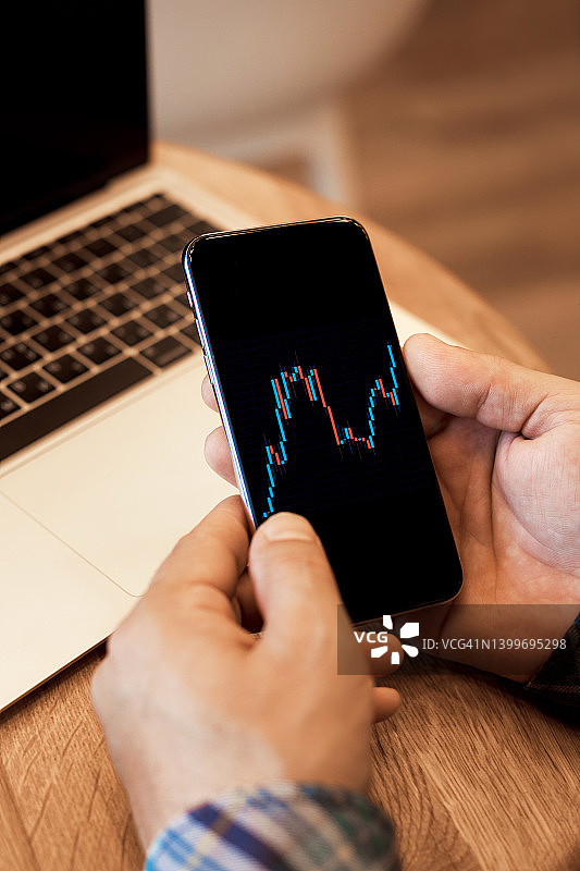Top view of man trader使用智能手机和笔记本电脑与金融图表和在线交易图片素材