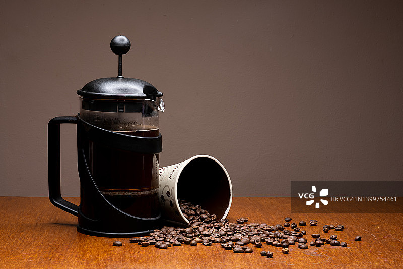 黑色过滤咖啡壶与马克杯和咖啡豆溢出图片素材