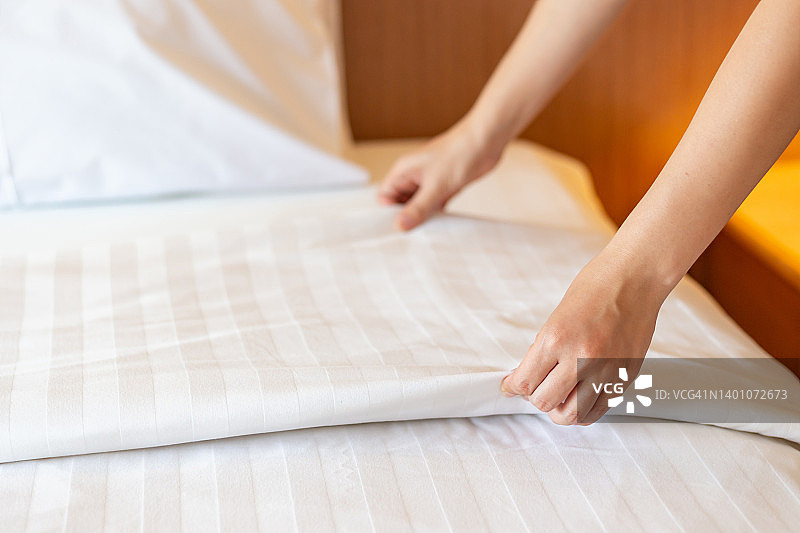 管家在卧室里套了一套白色床单。酒店的概念图片素材