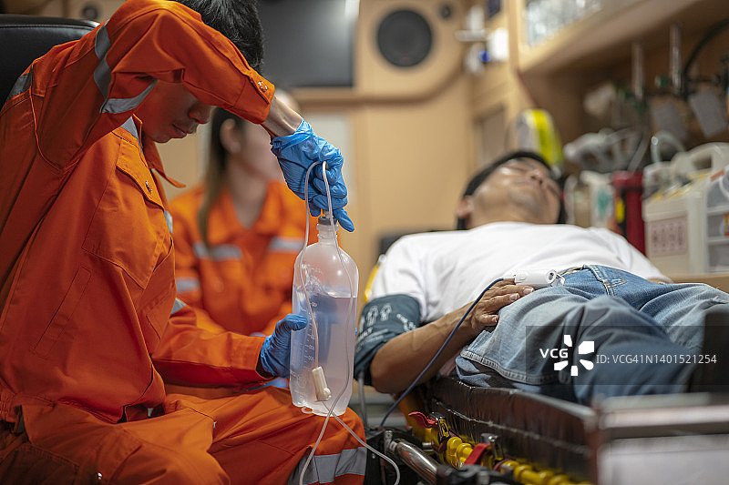 一名亚洲救护人员是一名全职救护人员，正在为事故受害者提供急救，送往医院进行进一步治疗。图片素材