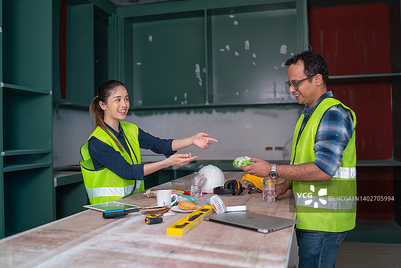 在建筑工地，亚洲女工在休息后给印度男子面包或糖果图片素材