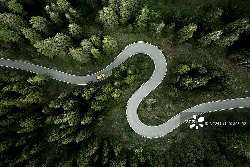 在森林中蜿蜒的山路上行驶的汽车鸟瞰图图片素材