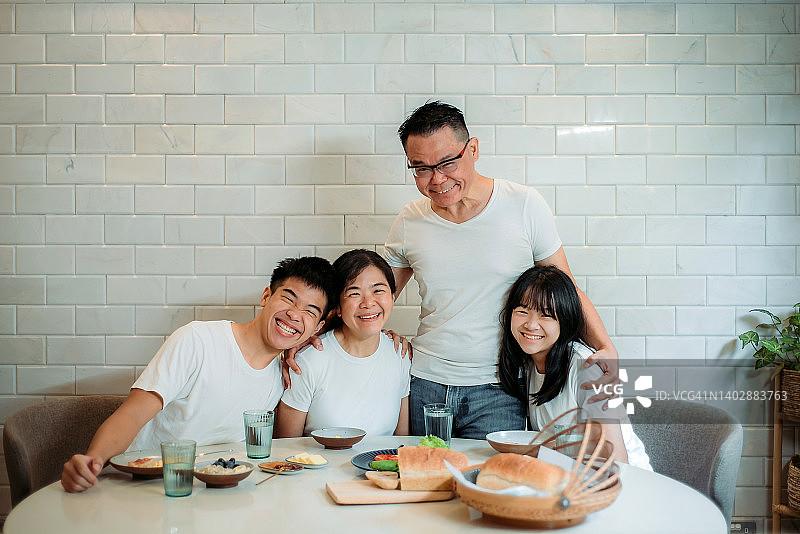 亚洲华人幸福的四口之家在家里的餐厅里一起吃早餐图片素材