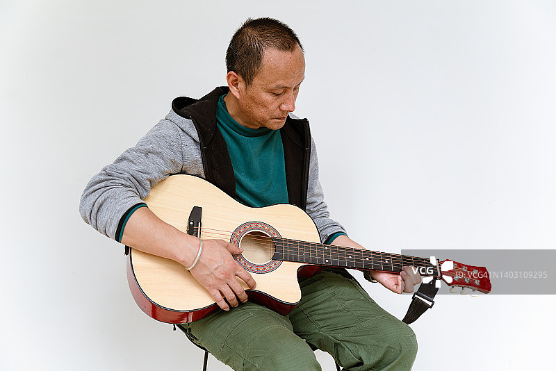 一个正在弹吉他的亚洲中年男子图片素材