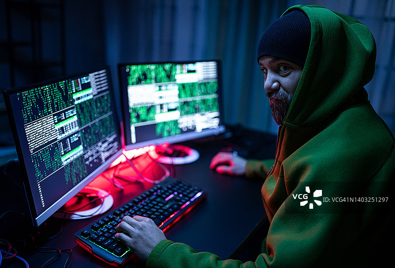 黑客在暗室里操作电脑，侧视图。图片素材